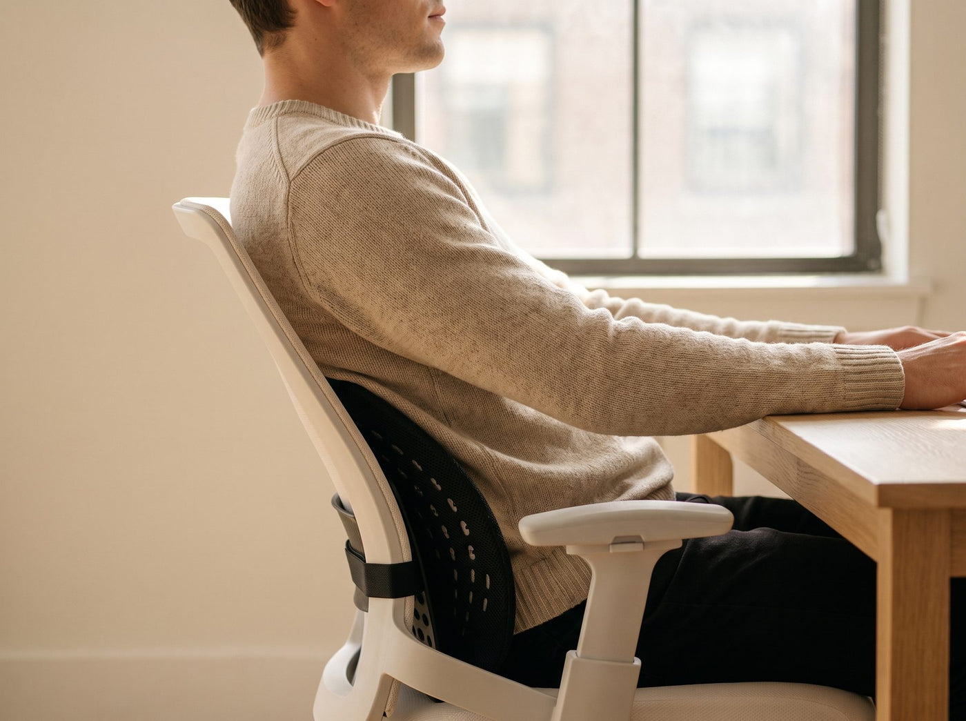 A person sitting back against the Uprite lumbar support at a desk